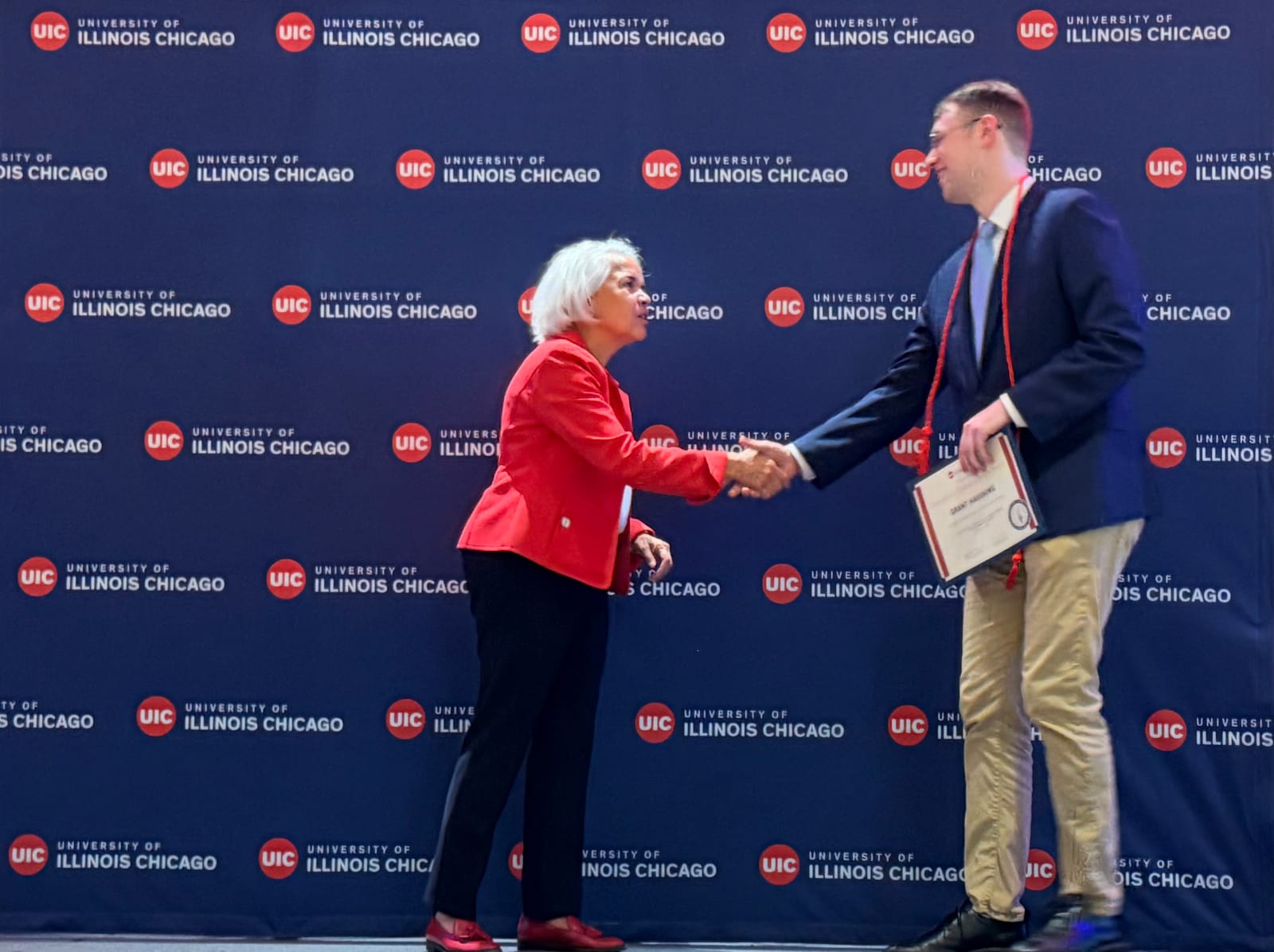 Grant Hauskins shaking hands with UIC Chancellor Marie Lynn Miranda at the Chancellor's Student Service Leadership Award ceremony, April 2026